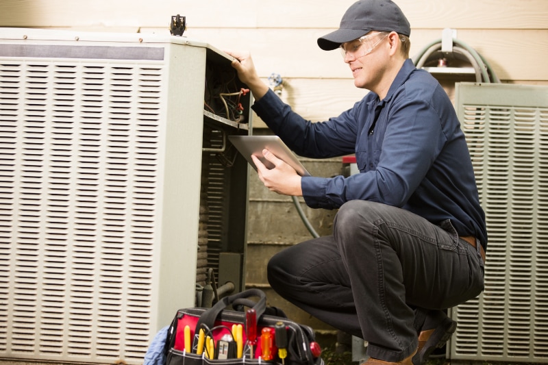 Repair man fixing air conditioning unit